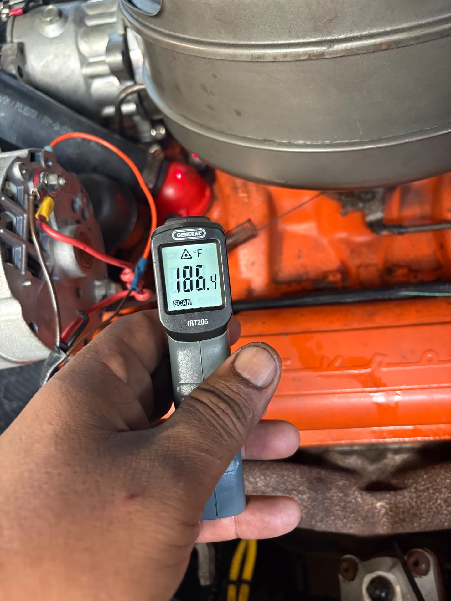 Technician checking a classic car engine temperature with a digital infrared thermometer