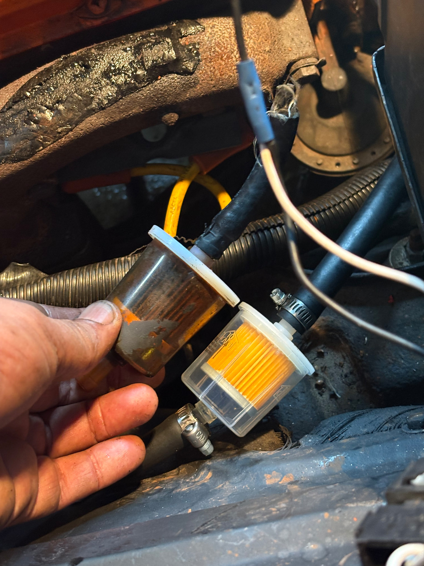 Old clogged fuel filter next to a newly installed clean fuel filter in an engine bay